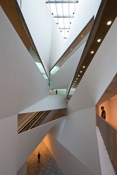 two people are standing in the middle of a building with high ceilings and wooden slats