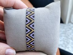 a person holding onto a pillow with a beaded bracelet on it