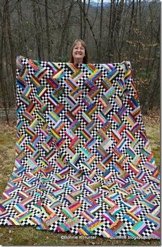 a woman is holding up a colorful quilt