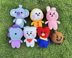 several crocheted stuffed animals sitting in the grass together, all wearing different outfits