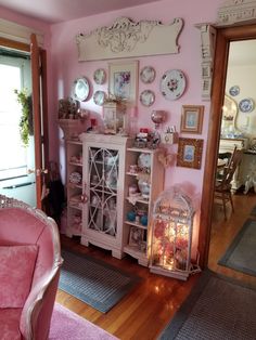 a living room with pink walls and furniture in the corner, including a birdcage