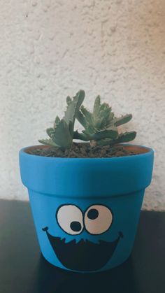 a potted plant with an angry face painted on it's side, sitting on a table