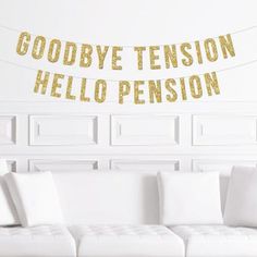 a living room with white couches and gold foil letters on the wall above them