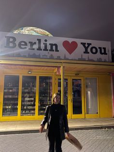 a woman is walking down the street in front of a store with a large sign that says berlin you