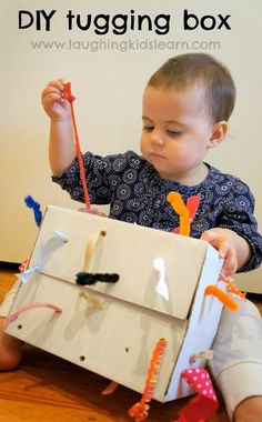 a young child is playing with a box made out of paper and scissors on the floor