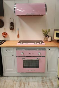 a pink stove top oven sitting inside of a kitchen next to a wall mounted oven