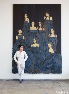 a woman standing in front of a large painting