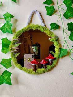 a mirror hanging on the side of a wall next to green leaves and ivys