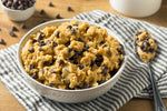 a bowl filled with oatmeal and raisins next to a glass of milk