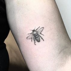 a small bee tattoo on the left inner arm and lower arm, it is black and white