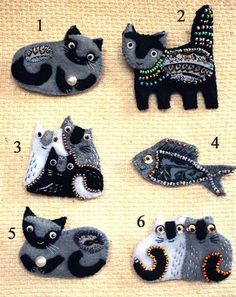 a group of cats made out of felt sitting on top of a cloth covered surface