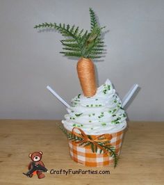 a cupcake with white frosting and green sprinkles on top is decorated like a carrot