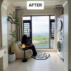 a woman sitting on a couch in front of a window next to a washer and dryer