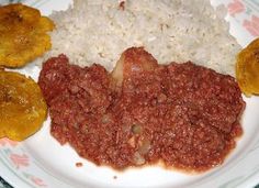 a white plate topped with rice and meat next to two fried plantain patties