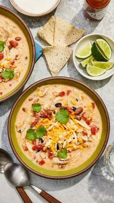 two bowls filled with white bean chili and tortilla chips on top of a table