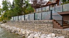 a stone wall next to a body of water with stairs leading up to the house