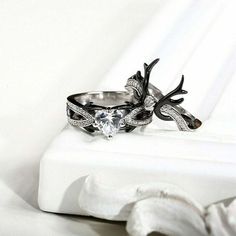 two wedding rings with antlers on them sitting on a white surface next to each other