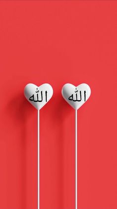 two heart shaped lollipops with arabic writing on them against a red background