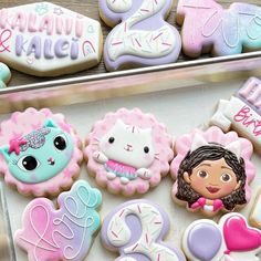 decorated cookies in the shape of princesses and cats are displayed on a tray for sale