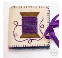 a piece of cloth with a purple ribbon on it and a spool of thread