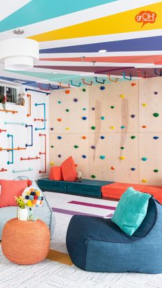 a room with colorful furniture and climbing wall in the background, there is also a couch that has pillows on it