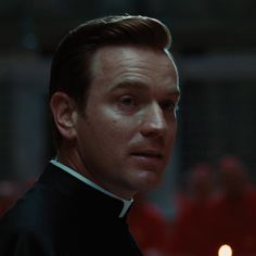 a close up of a person wearing a priest's uniform and looking at the camera