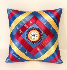 a blue, yellow and red decorative pillow on a white surface with the words around it