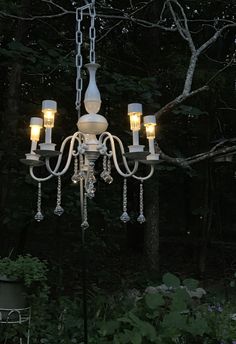 a white chandelier hanging from a tree in the dark