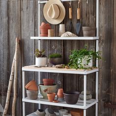 a shelf filled with pots and plants next to a wooden wall