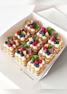 there are many small desserts in the box on the table and one is decorated with strawberries, raspberries, blueberries