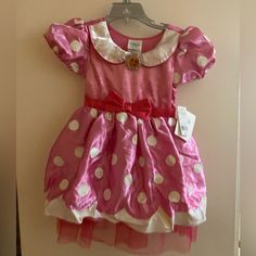 a pink and white polka dot dress hanging on a wall with a tag attached to it