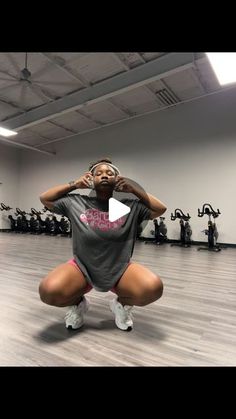 a woman squatting on the floor with her hands behind her head