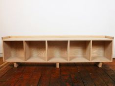 a wooden shelf sitting on top of a hard wood floor next to a white wall