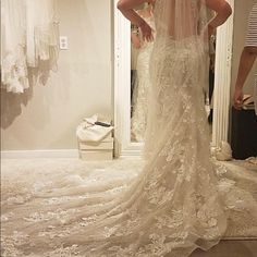 a woman standing in front of a mirror wearing a wedding dress with an open back