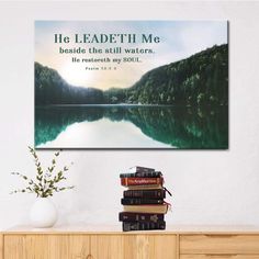 a book shelf with books on top of it and a painting in the background that says, he leadeth me beside the still waters