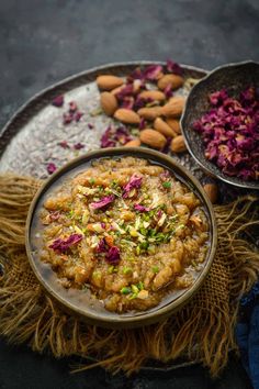 two bowls filled with food sitting on top of a metal tray next to nuts and dried flowers