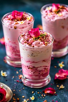 three desserts with pink frosting and sprinkles on a blue surface