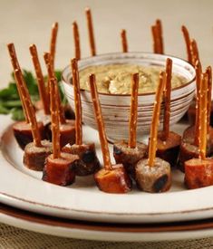 small appetizers are arranged on a plate with toothpicks and dip in the middle