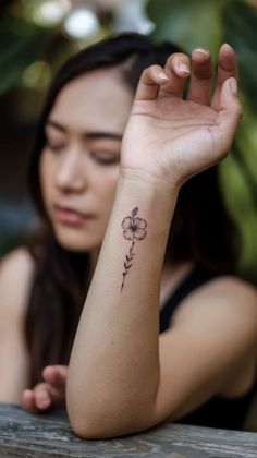 a woman with a flower tattoo on her left arm and right arm behind her head