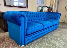 a blue couch sitting on top of a carpeted floor next to a framed mirror