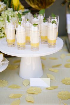 there are many glasses on the table with drinks in them and some flowers around it