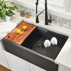 a kitchen sink with two lemons on the cutting board next to it and a potted plant