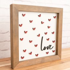 a wooden frame with red hearts and the word love written in cursive writing