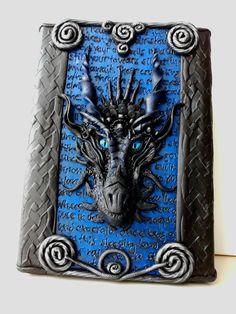 a blue and black dragon head is mounted on a plaque with writing in the background