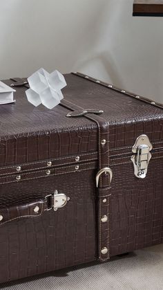 an old brown suitcase sitting on the floor next to a wall with papers sticking out of it