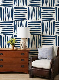 a living room with blue and white wallpaper on the walls, a brown chair next to a wooden dresser