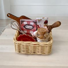 a wicker basket with utensils and other kitchen items in it on a table