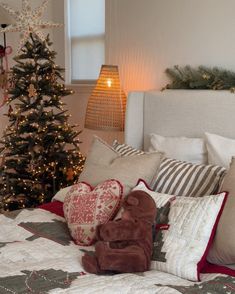 a christmas tree in the corner of a bedroom next to a bed with pillows and blankets