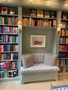 a room filled with lots of books on top of a book shelf next to a couch