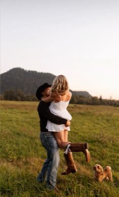 a man and woman hugging in a field with a dog